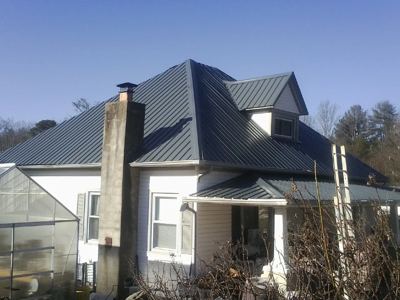 Dark blue standing seam metal roof on a white farmhouse with dormer — Slate & Tile Roof Repair by Roofing Brothers in Wartrace
