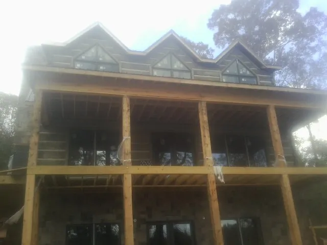 Dormers and porch framing on a large log home under construction — Roof Coating work by our crew in Wartrace