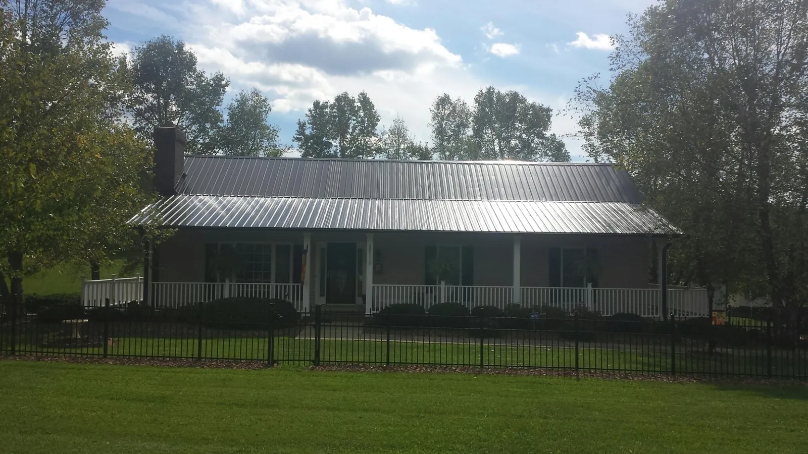 Gray metal roof on a brick ranch with a full width front porch — Gutter Guard Installation work by our crew in Wartrace