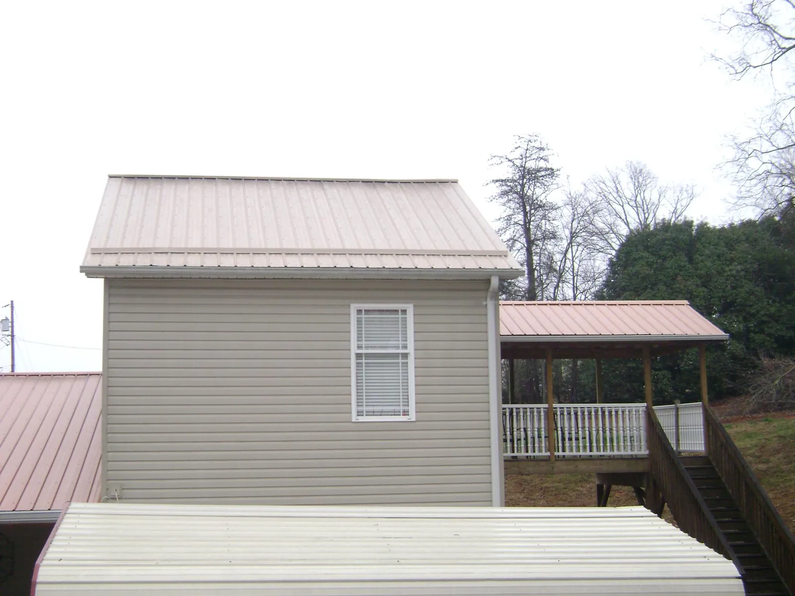 Tan metal roofs on a two story addition and attached porch, from a Roof Replacement job in Wartrace