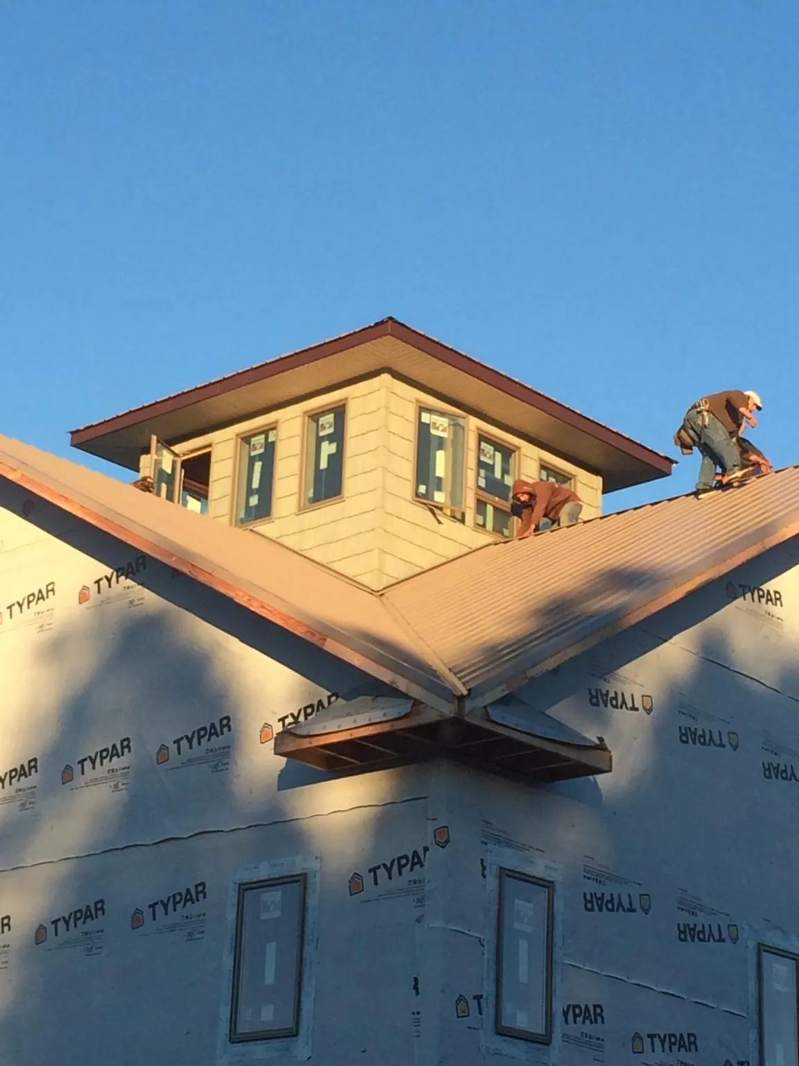 Roofers working around a rooftop cupola on a new metal roof at sunset — Roof Waterproofing in Wartrace by Roofing Brothers